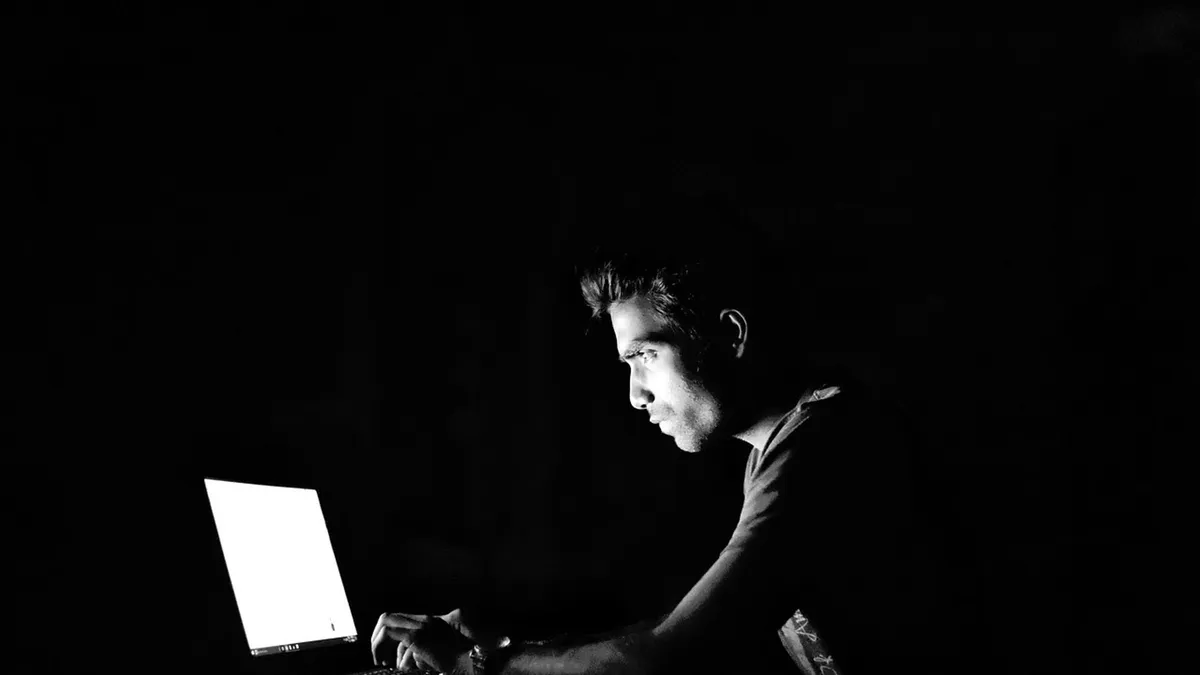 Person sitzt im Dunkeln vor einem Laptop